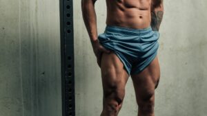 Young strong man posing and flexing his quadriceps legs muscles
