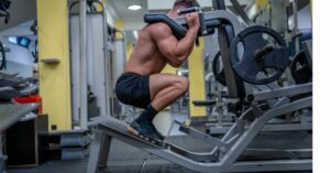 Man doing quadriceps exercise on hack squat machine at gym ,.
