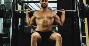 Portrait of a Strongman Squatting with Weights in a Gym