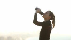 Runner hydrating drinking water after exercise