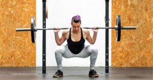 Young girl doing a back squat with a barbell