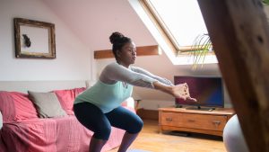 A Woman Doing Squats while Stretching Her Arms