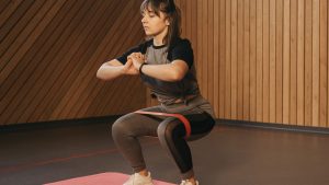 A Woman Doing the Squats with a Resistance Band