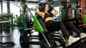 Young Fit Slim Woman Doing Squats in a Hack Exercise Machine