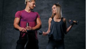 attractive-fitness-couple-sporty-male-holds-barbell-slim-blond-female-holds-dumbbells-grey-background.jp