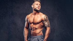 handsome-shirtless-tattooed-bodybuilder-with-stylish-haircut-beard-wearing-sports-shorts-posing-studio-isolated-dark-background.j