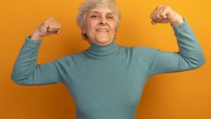 smiling-old-woman-wearing-blue-turtleneck-sweater-looking-side-doing-strong-gesture-isolated-orange-wall.jpg