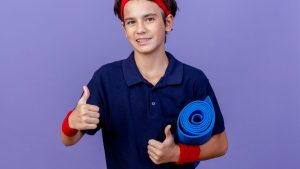 Free photo smiling young handsome sporty boy wearing headband and wristbands with de
