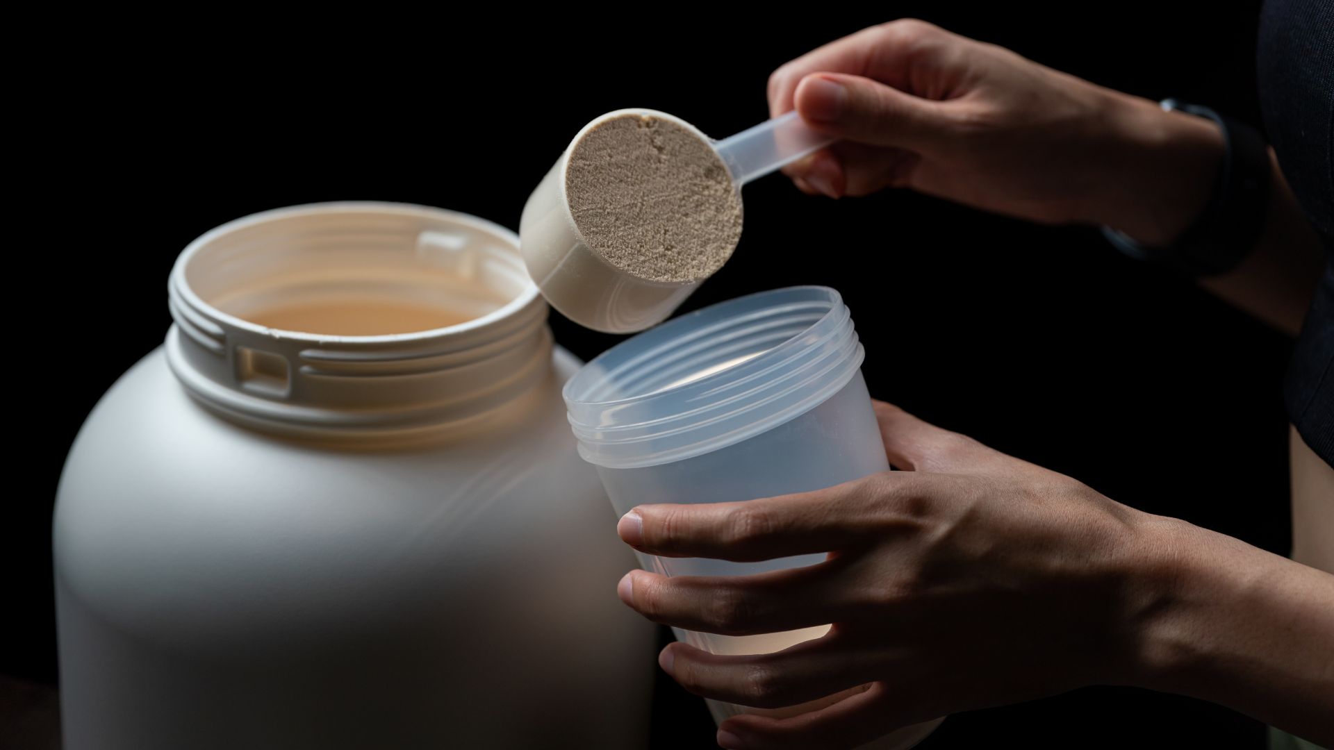 Close Up of Person Putting Protein Powder in Container