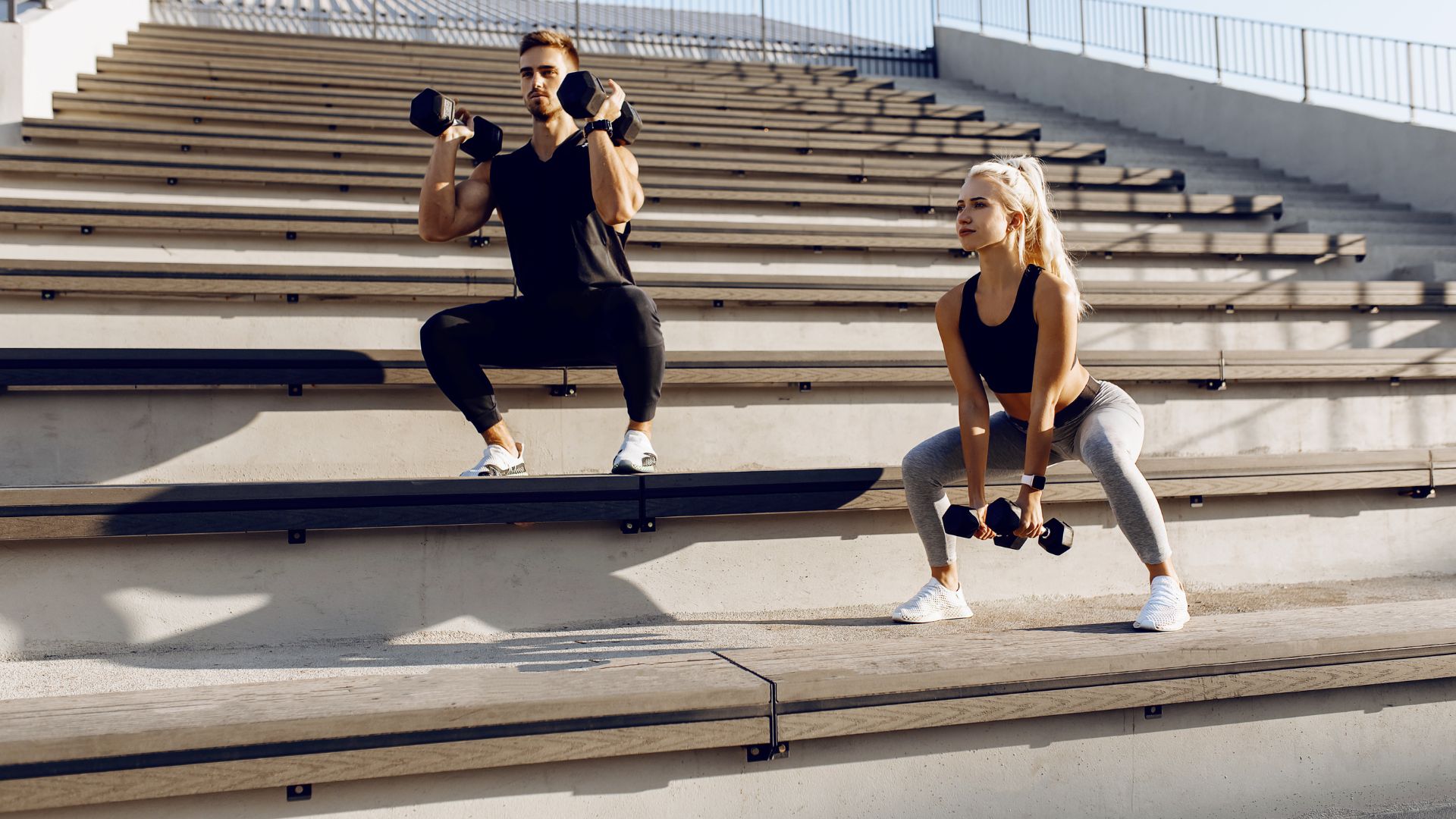 Sporty Young Couple in Sportswear Doing Squats with Dumbbells Outdoor