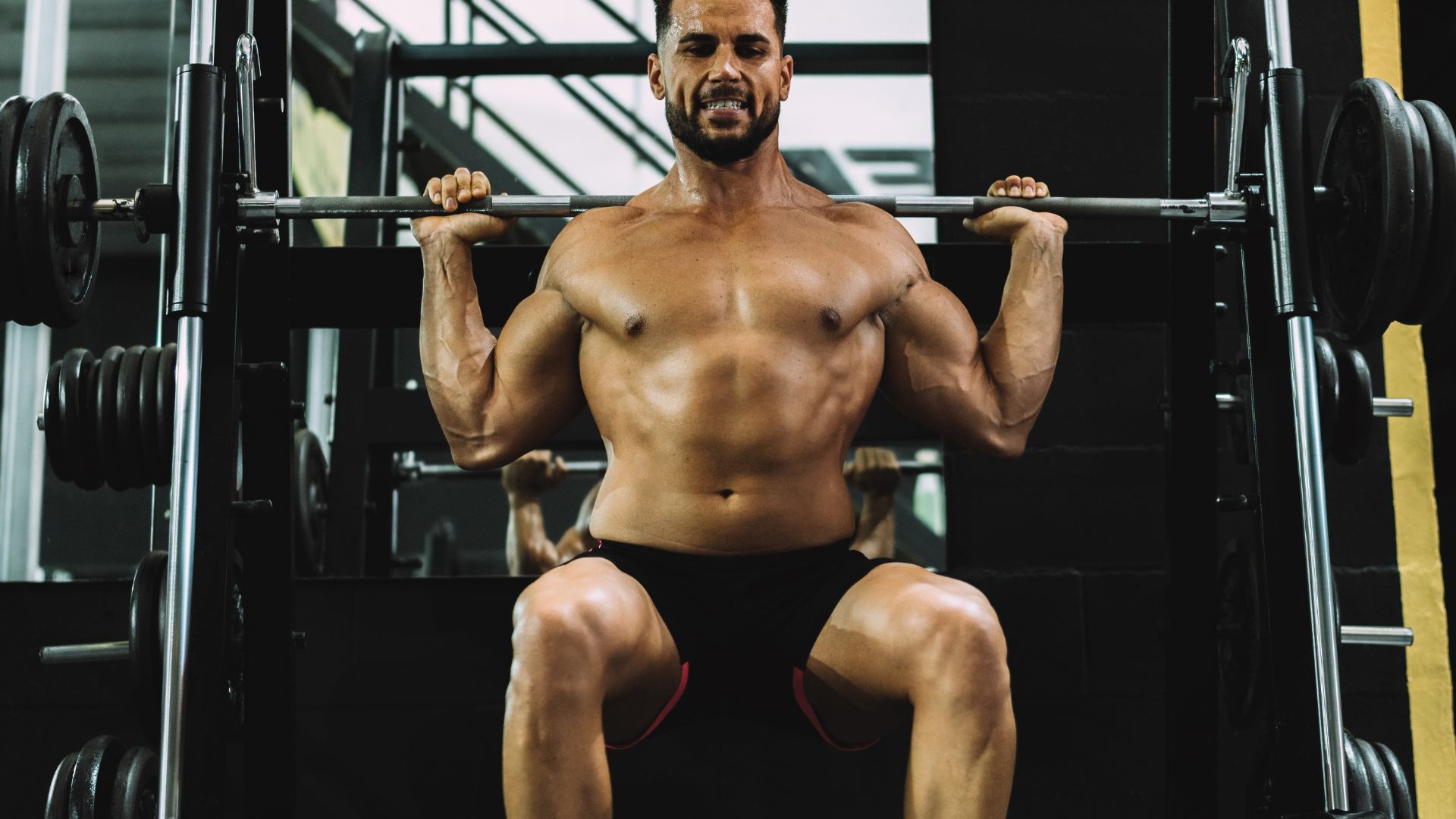 Portrait of a strongman squatting with weights in a gym
